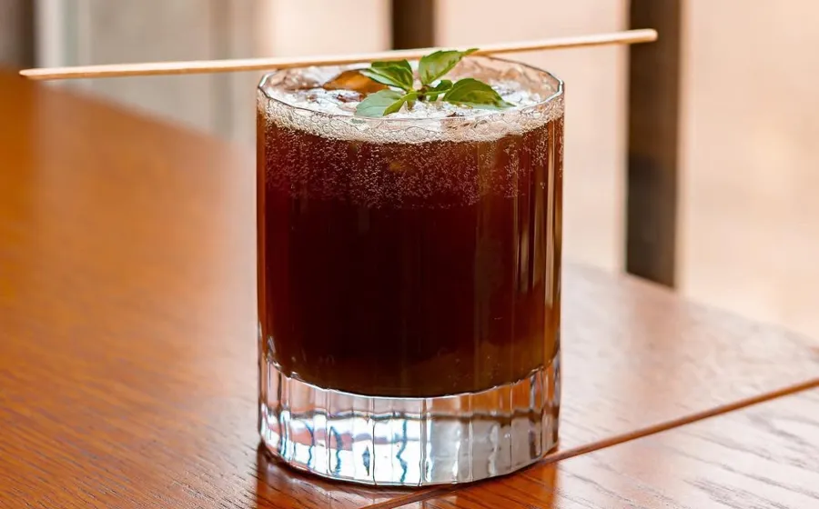 Cold brew de tamarindo de Congreso Café, con hojas de menta, sobre la barra de madera.